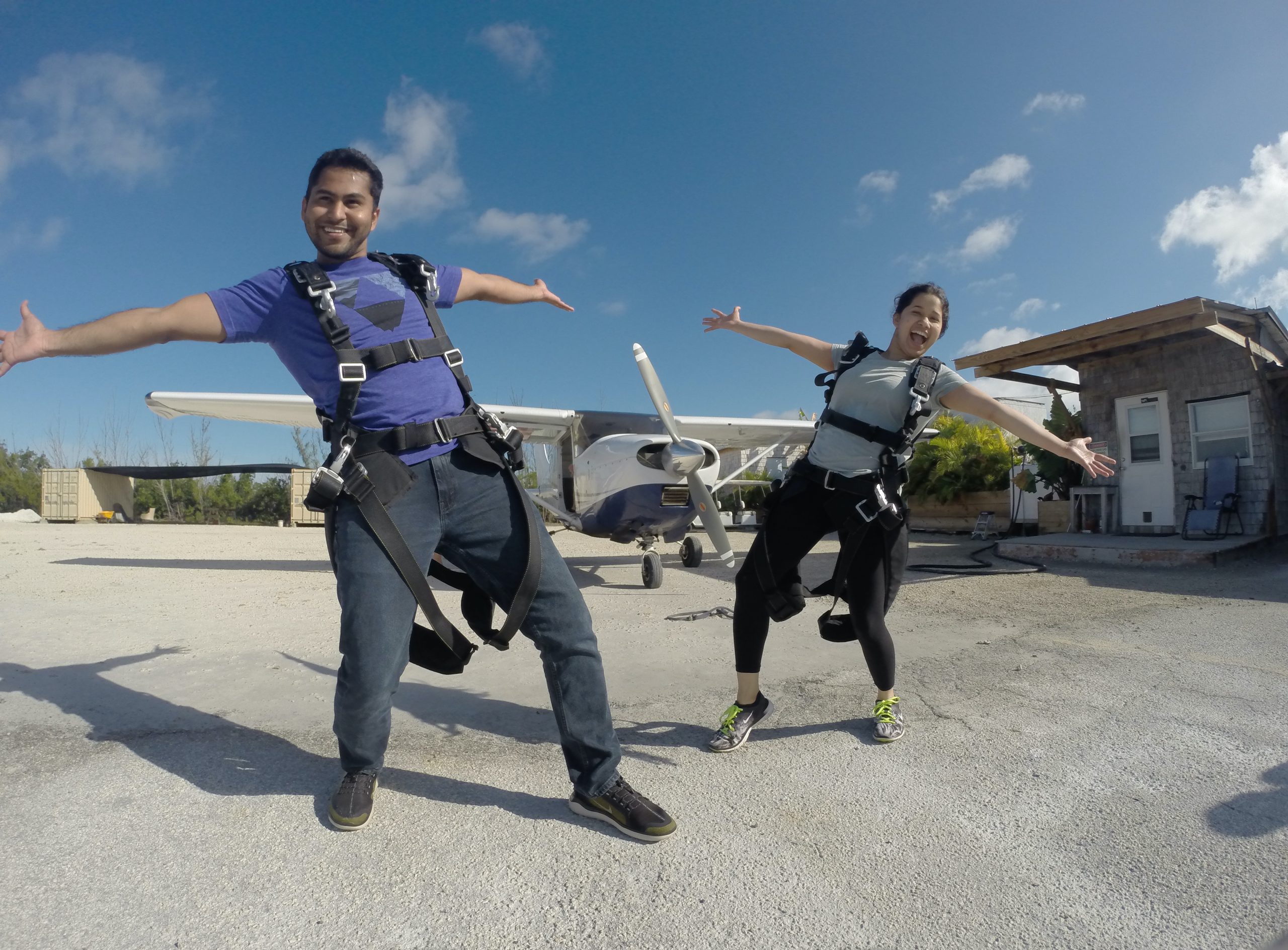 A male and female tandem jumper pose in front of the airplane. 