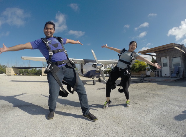 a man and woman posing in front of a skydiving plane