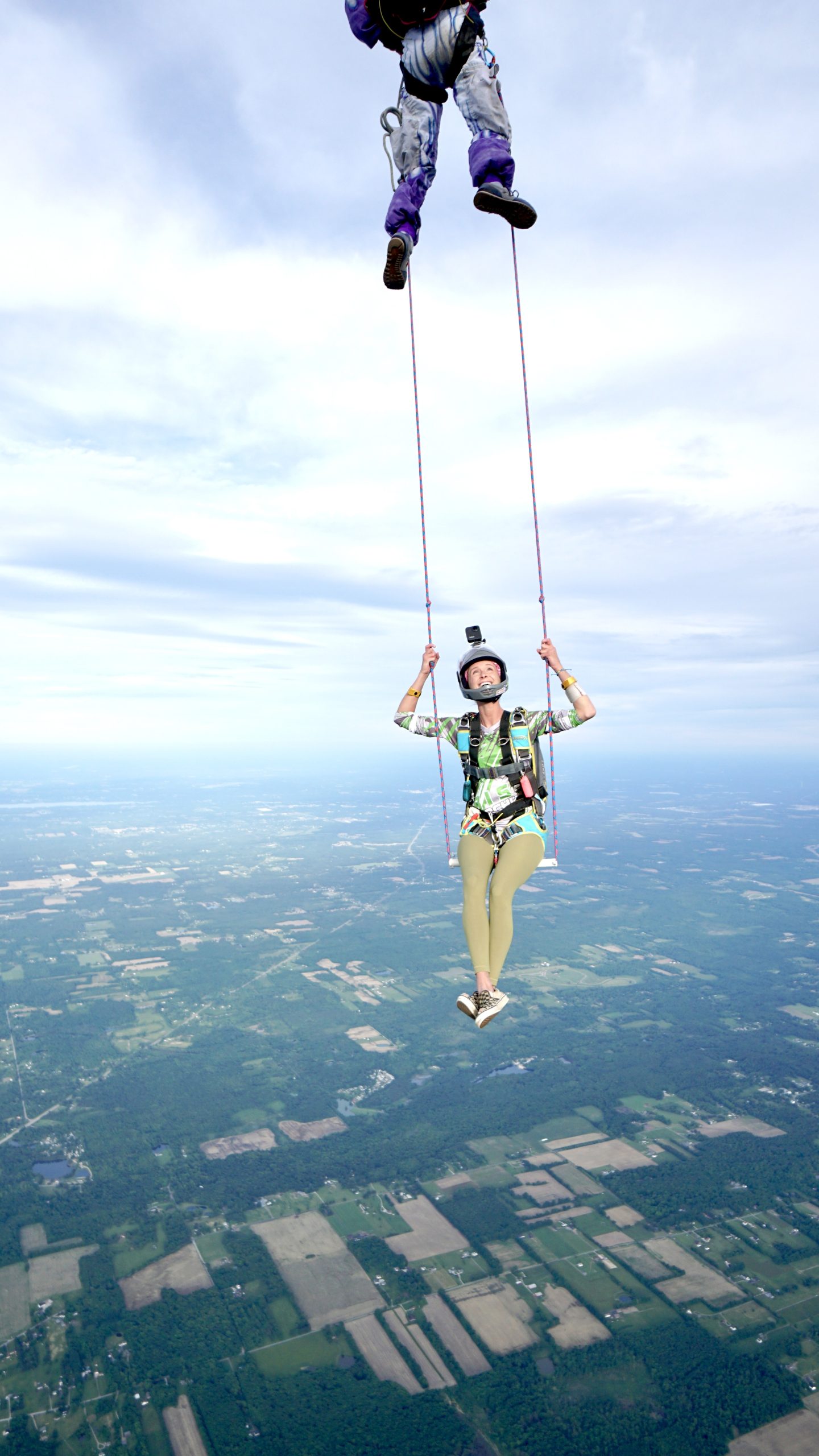 Author Cecilia Malise Sitting On Swing In Mid-Air Hanging From Fellow Skydivers' Feet