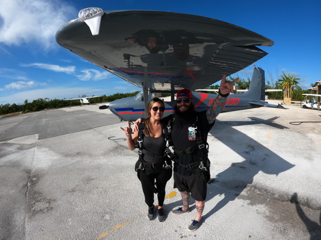 a couple celebrating in front of a skydiving plane