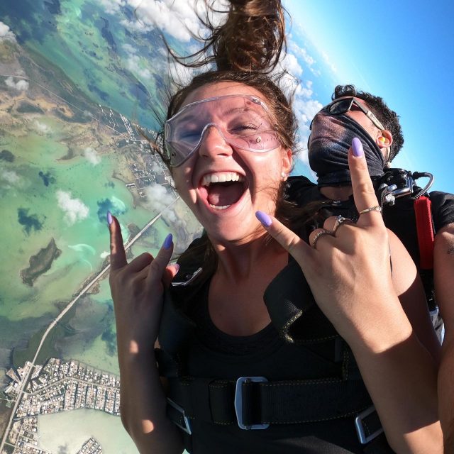 Young female smiles during the free fall portion of her skydive with Skydive Key West tandem instructor