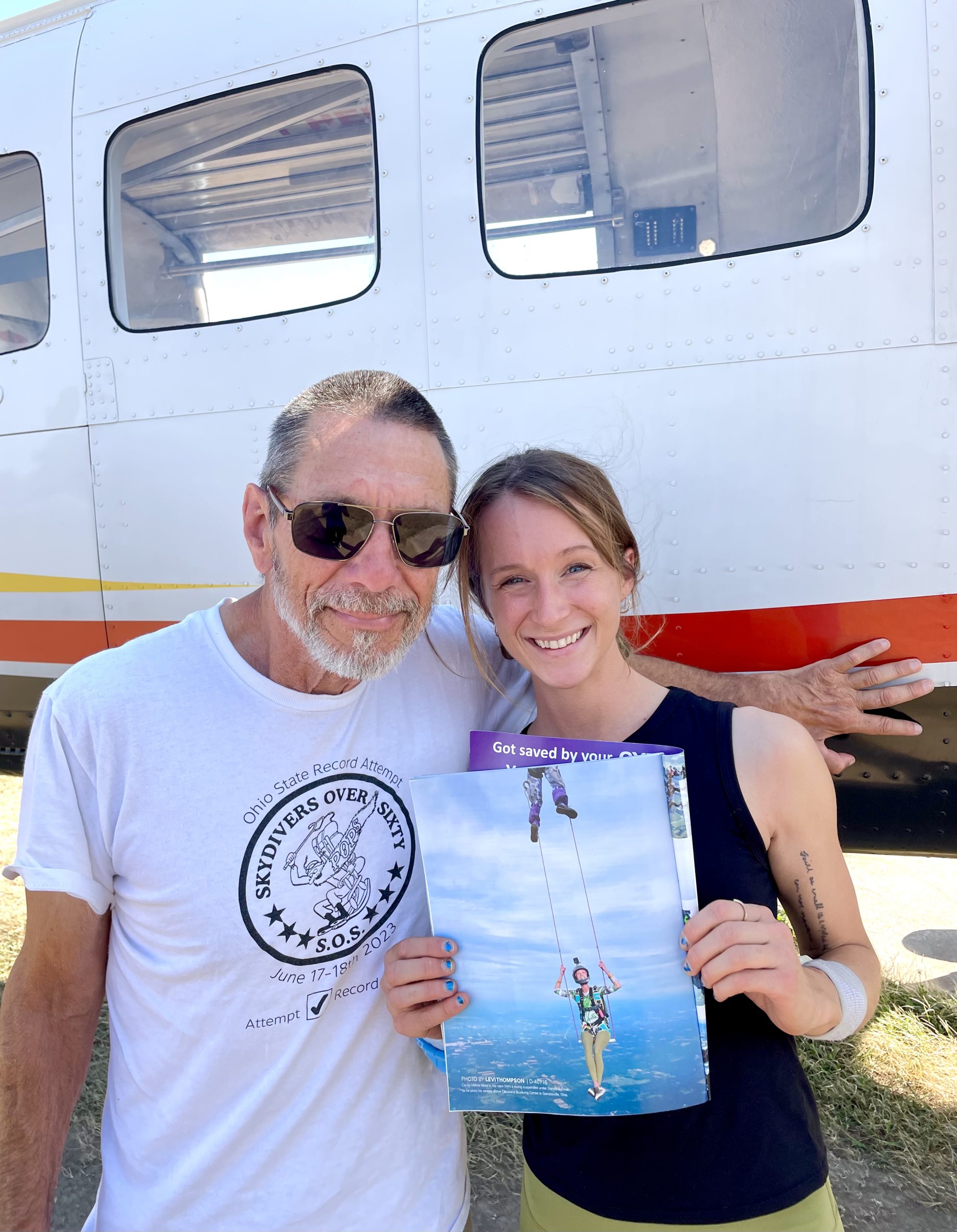 Author Cecilia Malise Holding Photo Of Herself Skydiving