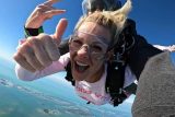 girl giving thumbs up in skydiving tandem freefall
