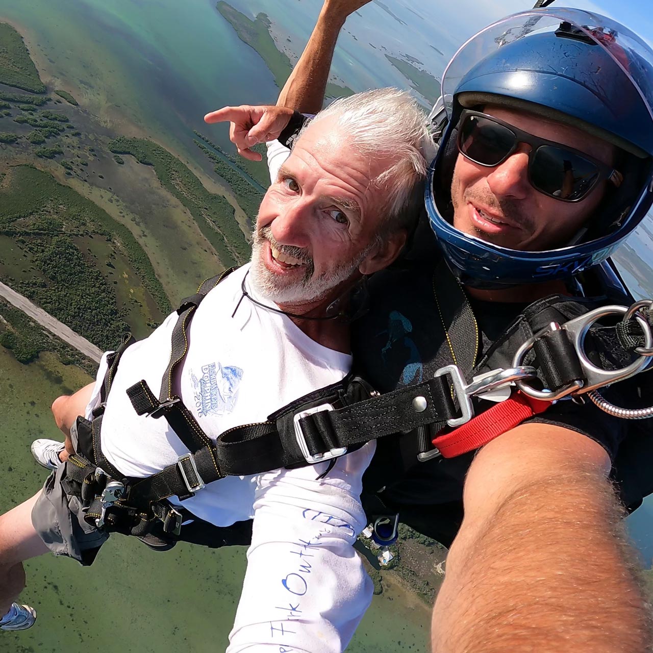 older gentlemen wearing a white long sleeve shirt smiles during his Florida Keys Skydiving experience