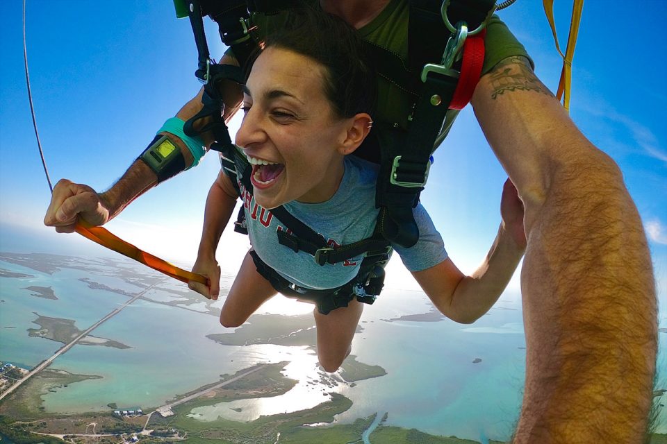 Woman smiles with glee looking over the beautiful water while Skydiving South Florida