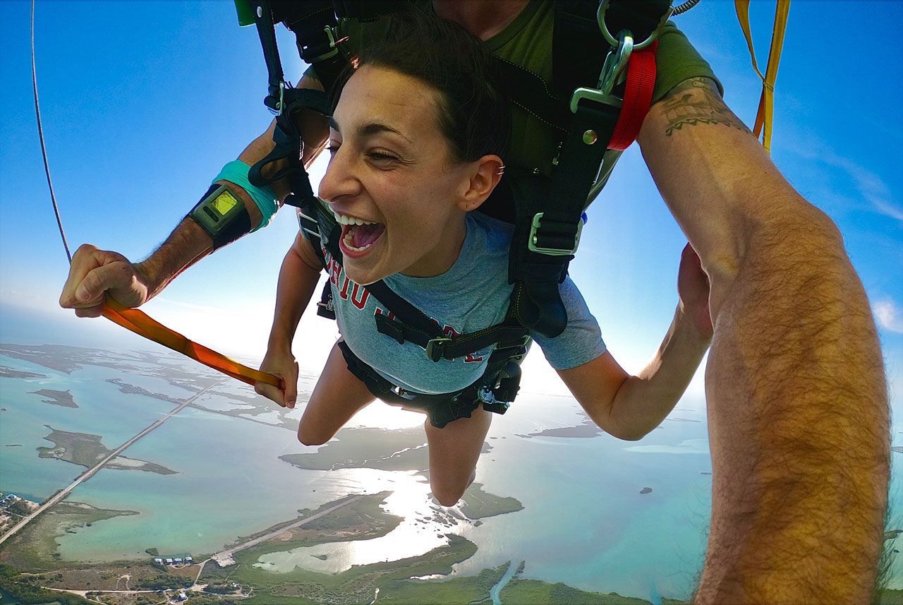 Woman smiles with glee looking over the beautiful water while Skydiving South Florida