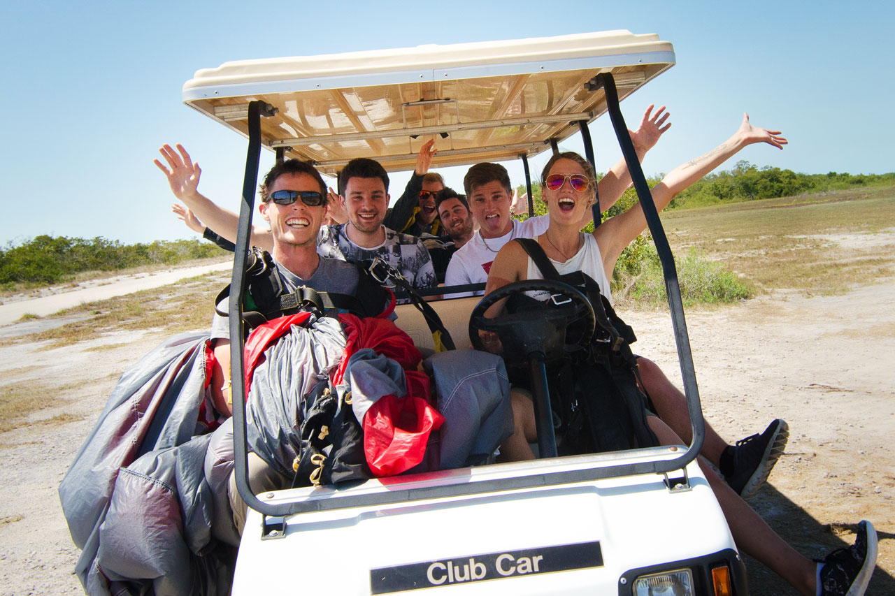 Group of young tandem jumps driving in golf cart to enjoy skydiving south Florida