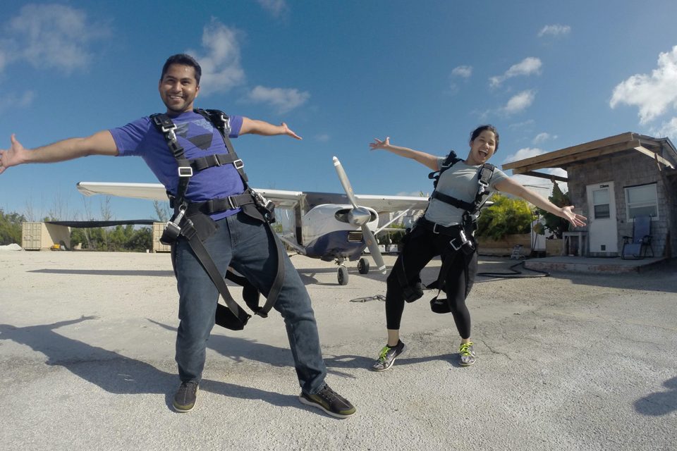 A male and female tandem jumper pose in front of the airplane.
