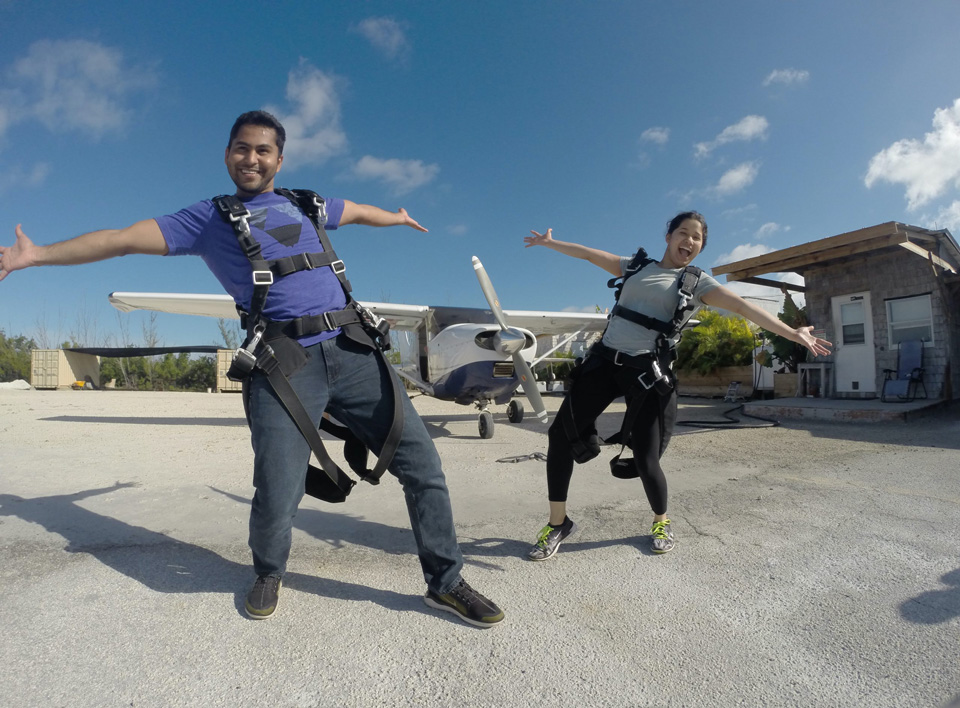 A male and female tandem jumper pose in front of the airplane.