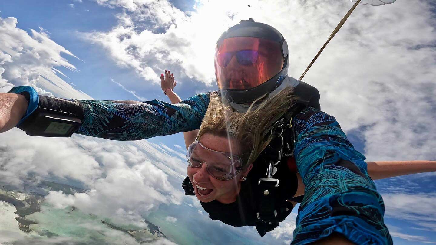 Girl smiling in freefall on a tandem skydive with her instructor.