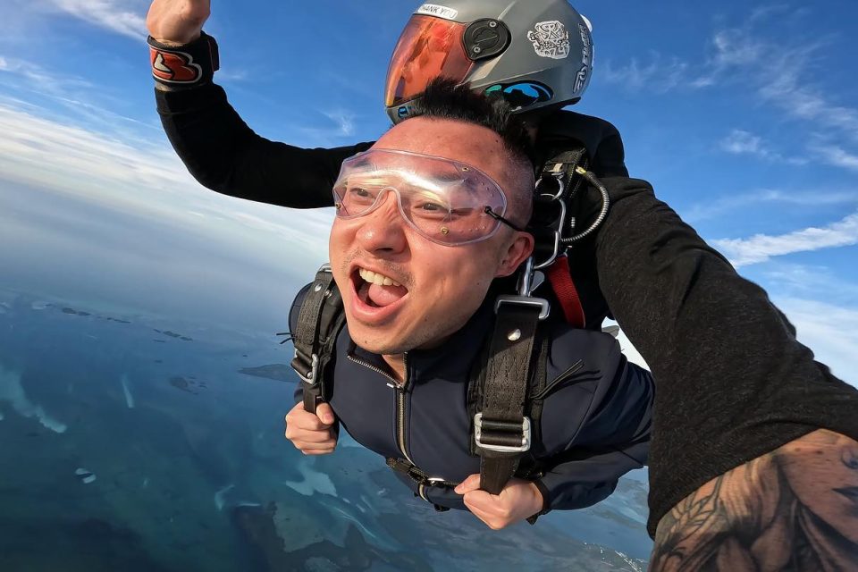 Man on a tandem skydive holding his harness