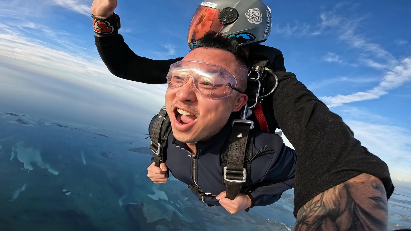 Man on a tandem skydive holding his harness