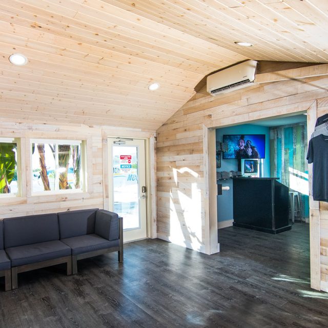 Skydive Key West facilities building with dark brown floors and soft wooden floors with a dark blue couch sitting next to entry door