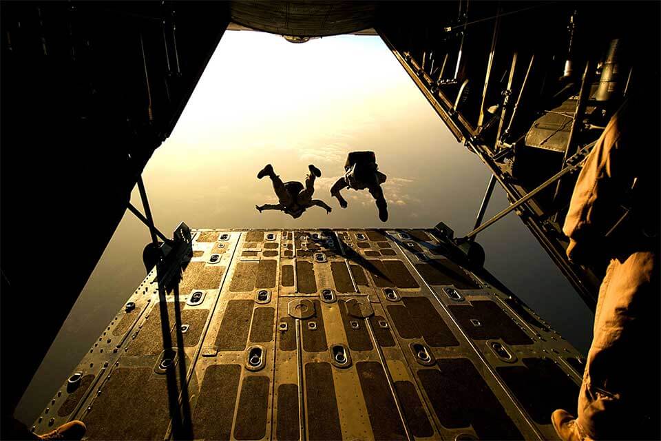 Two skydivers exit from the back of a tailgate airplane. 