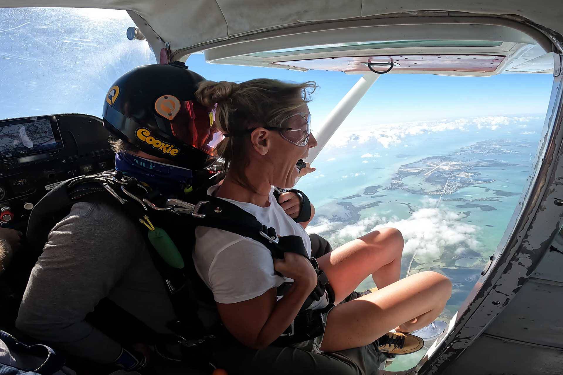 Female tandem skydiving student preparing to exit an airplane over the Florida Keys