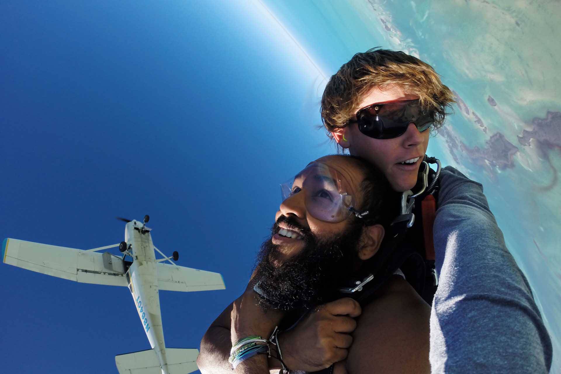 Young tandem jumper enjoying freefall while Skydive Key West airplane flies above him