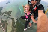 Young female wearing a pink shirt smiles during the canopy portion of her Skydiving South Florida experience