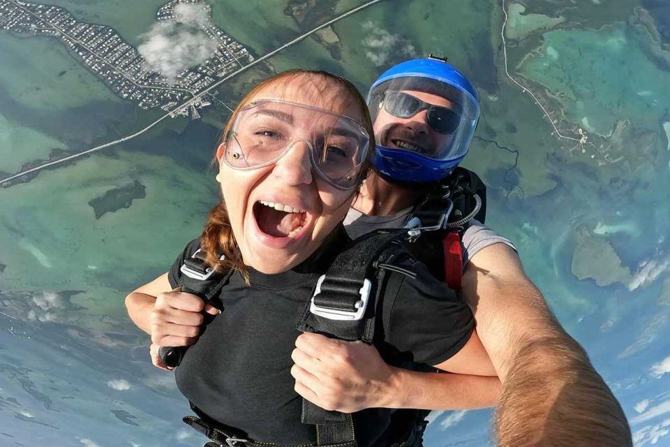Girl smiles with mouth wide open during a tandem skydive