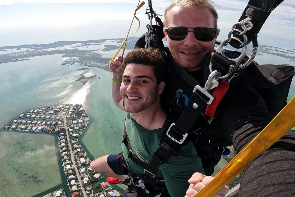 Young man in green shirt smiles while enjoying a peaceful canopy ride with Skydive Key West instructor