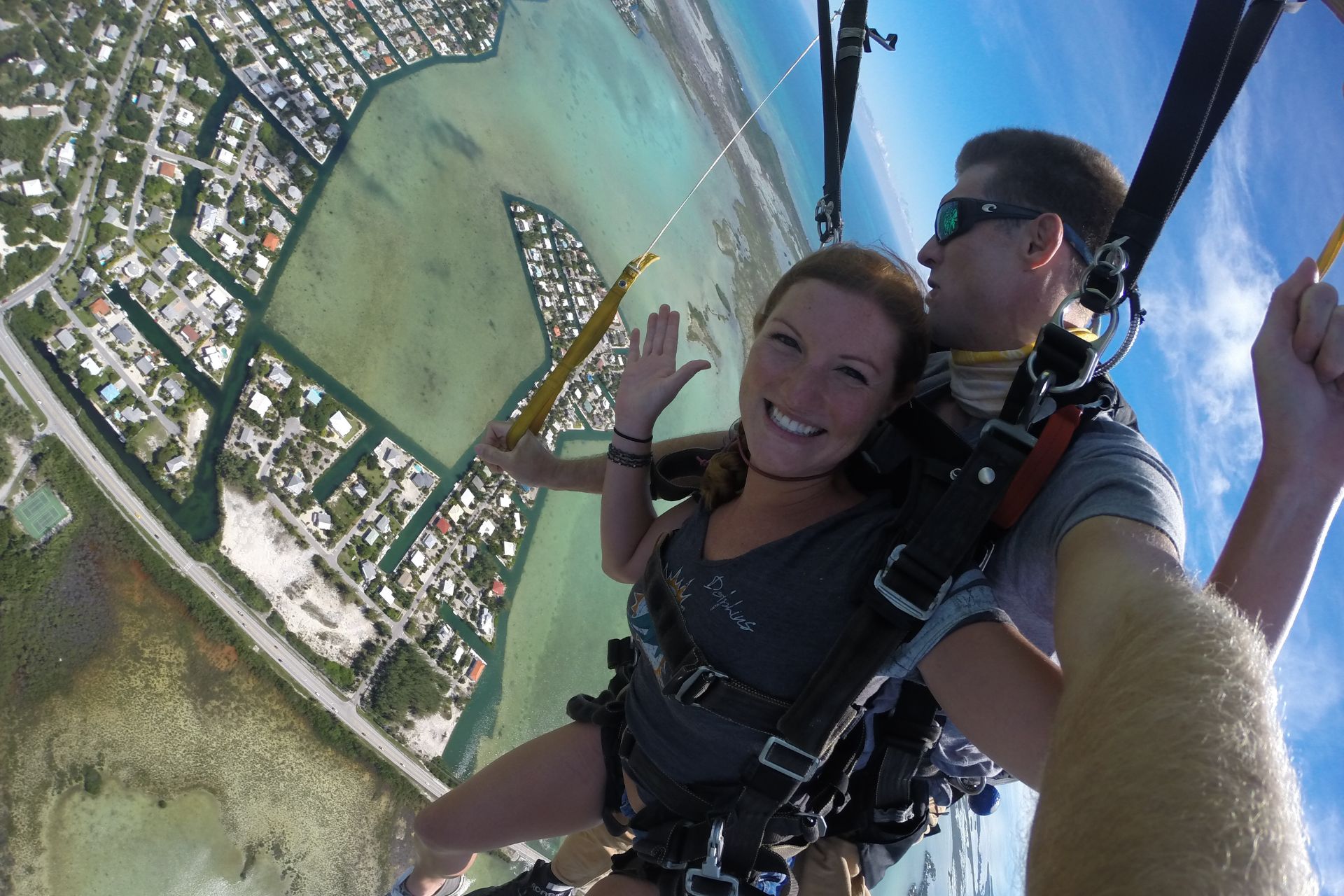 Female smiles at the camera under a skydiving canopy. 
