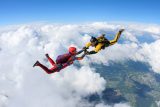 Two skydivers are falling against the background of the white clouds.