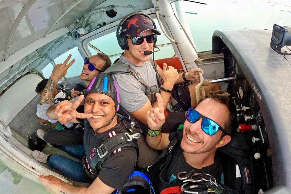 Group of men posing in a airplane on the ride up to a tandem skydive