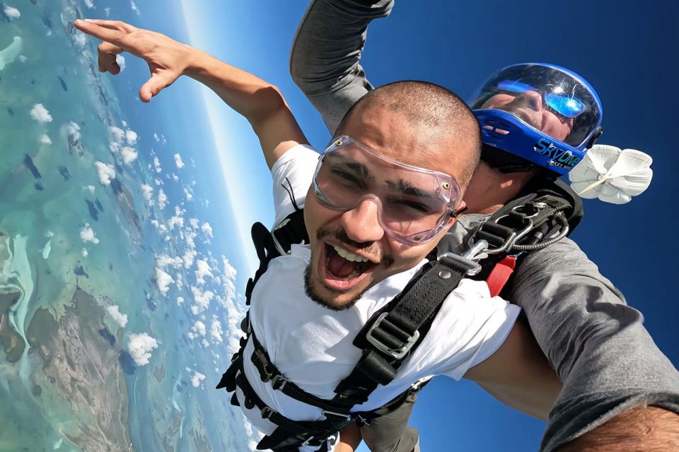 Man wearing white shirt and clear goggles tandem skydiving at Skydive Key West